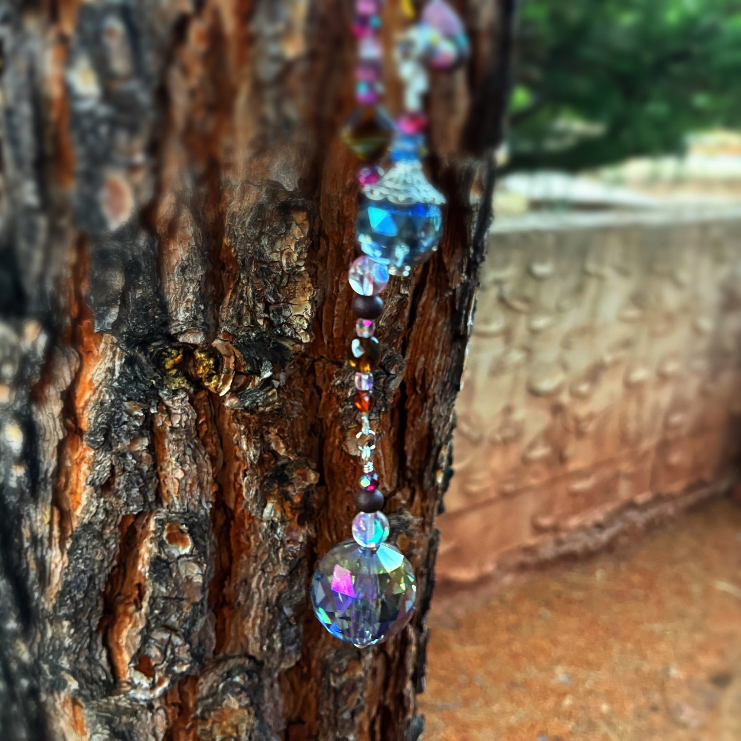 Decorative beaded string with colorful beads hanging on a tree trunk.