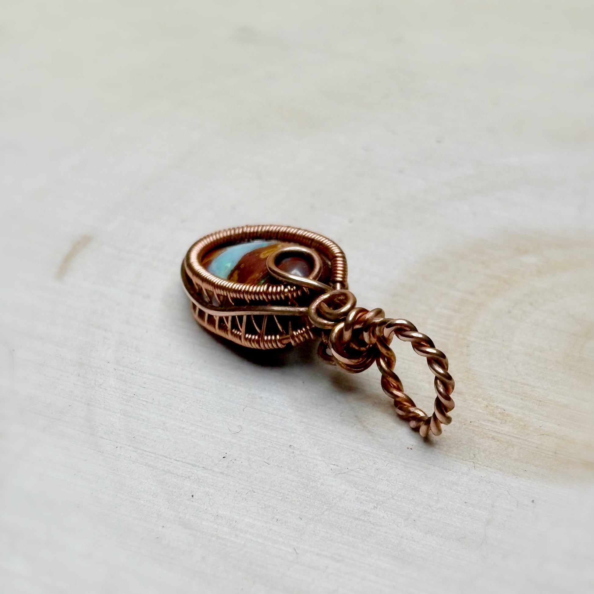 Copper wire-wrapped pendant on a light wooden surface