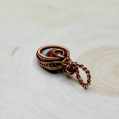 Copper wire-wrapped pendant on a light wooden surface