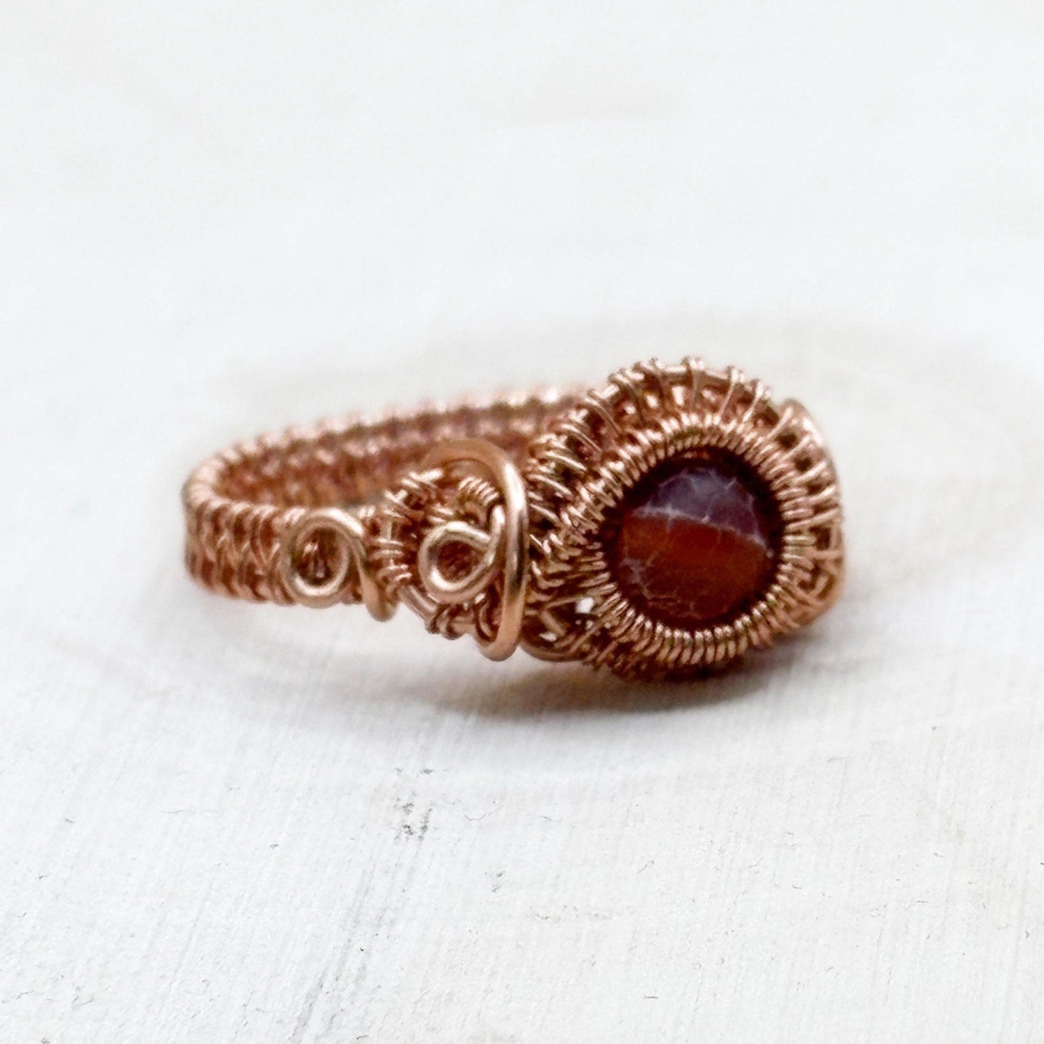 Copper ring with a red gemstone on a white background