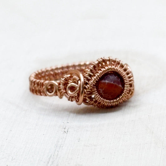 Copper ring with a red gemstone on a white background-p