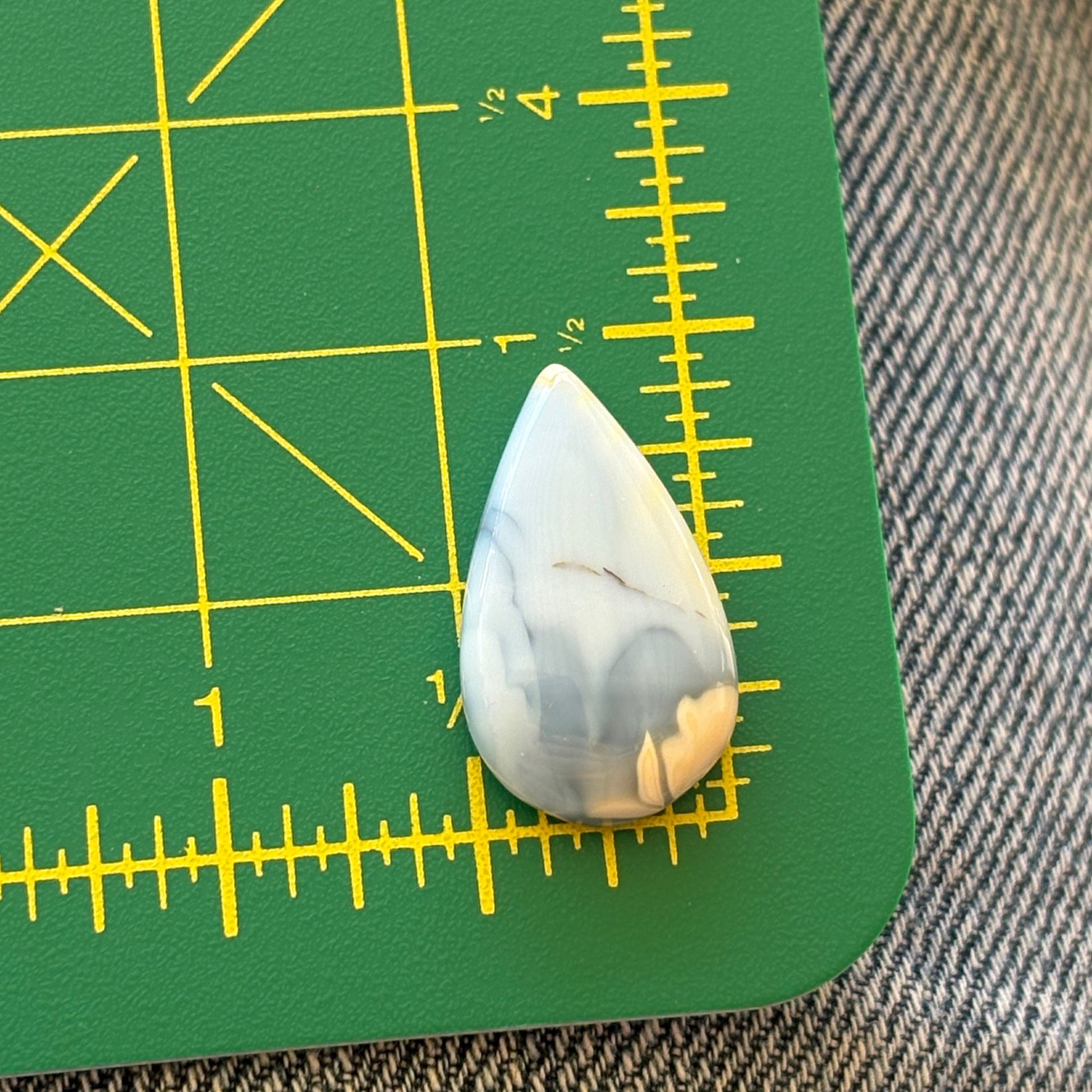 Teardrop-shaped stone on a green cutting mat with yellow measurements