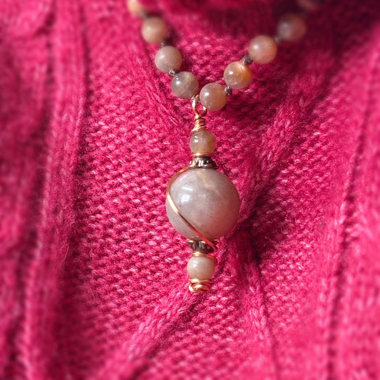 Necklace with pink beads on a pink textured fabric background