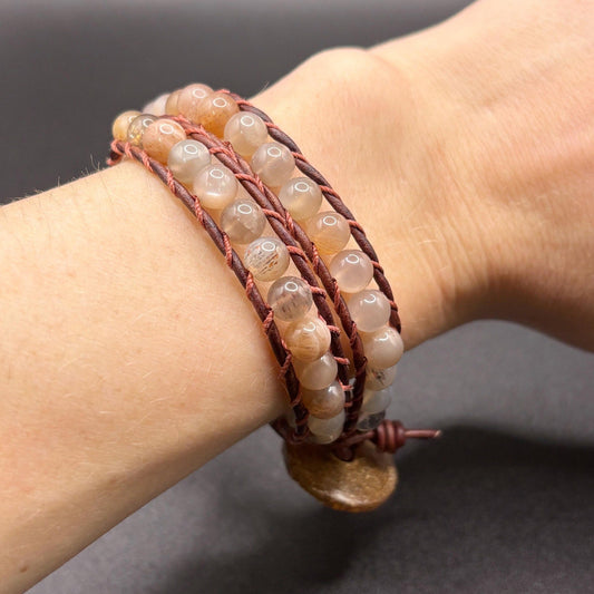 Close-up of a wrist wearing a beaded bracelet with a neutral background
