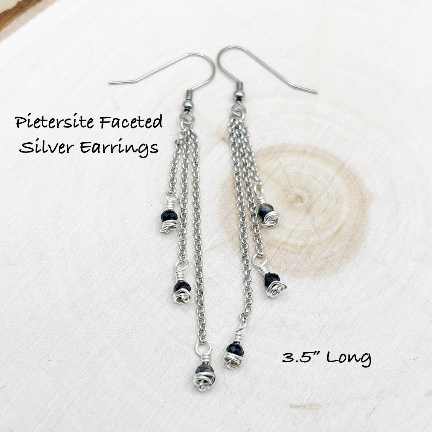 Chain style earrings sitting on a wood background with dark blue shiny stones