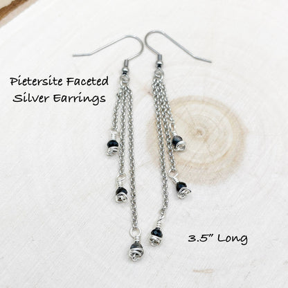 Chain style earrings sitting on a wood background with dark blue shiny stones