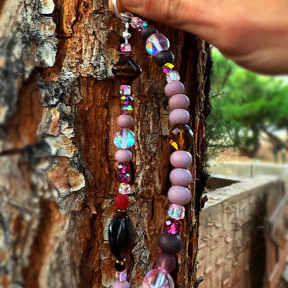 Colorful beaded sun catcher hanging on a tree trunk