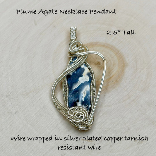 Plume Agate Necklace Pendant on a wooden surface with text describing its features.