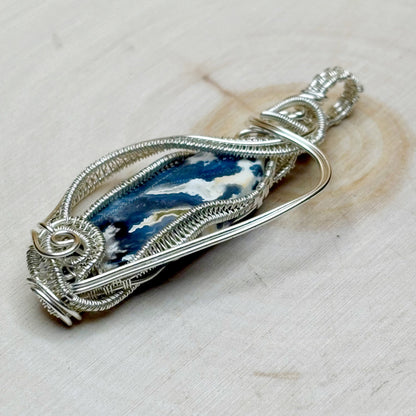 Silver wire-wrapped pendant with blue and white stone on a light background