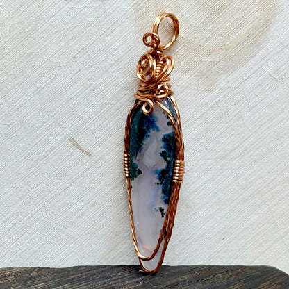 Decorative pendant with a purple and white stone on a textured surface
