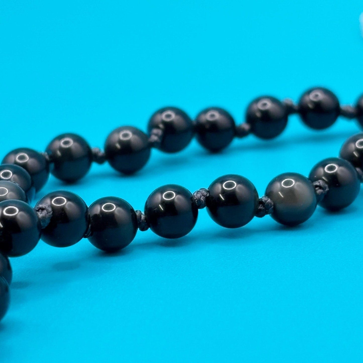 Black beaded necklace on a blue background