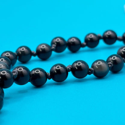 Black beaded necklace on a blue background