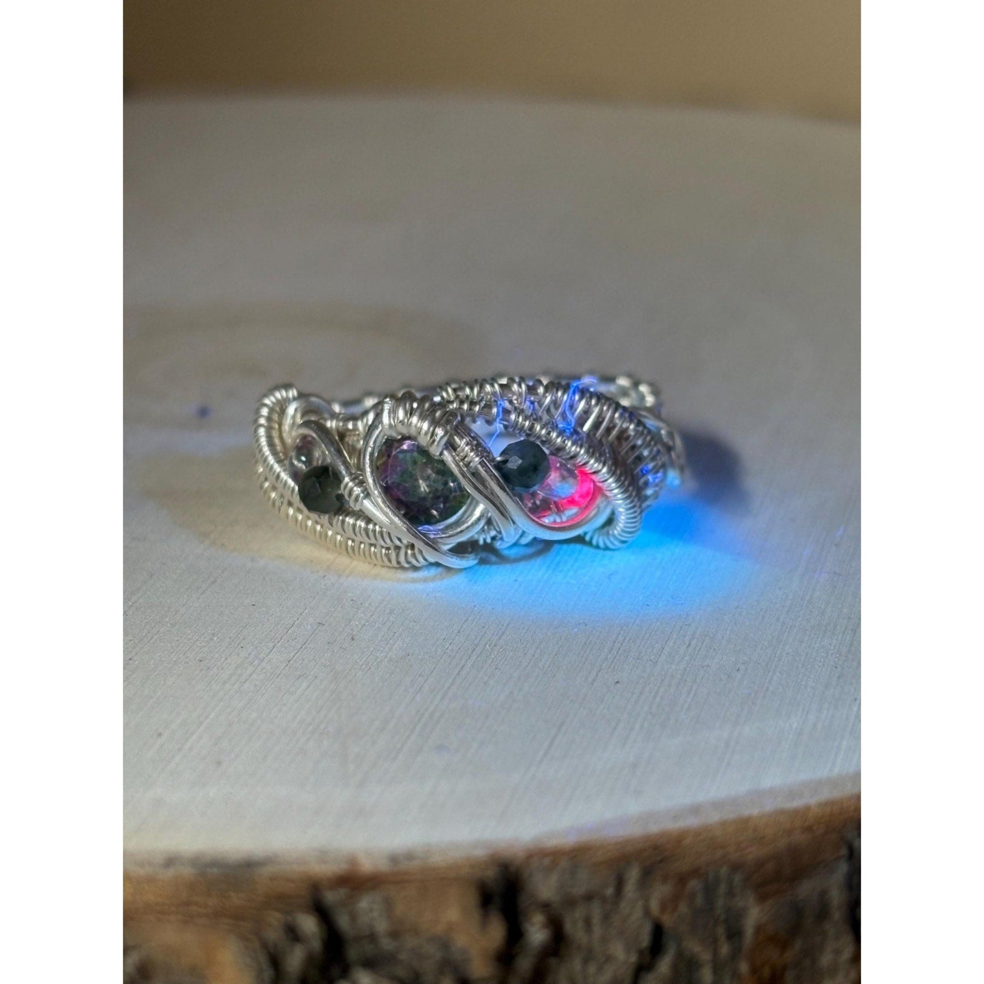 Silver ring with embedded stones on a wooden surface