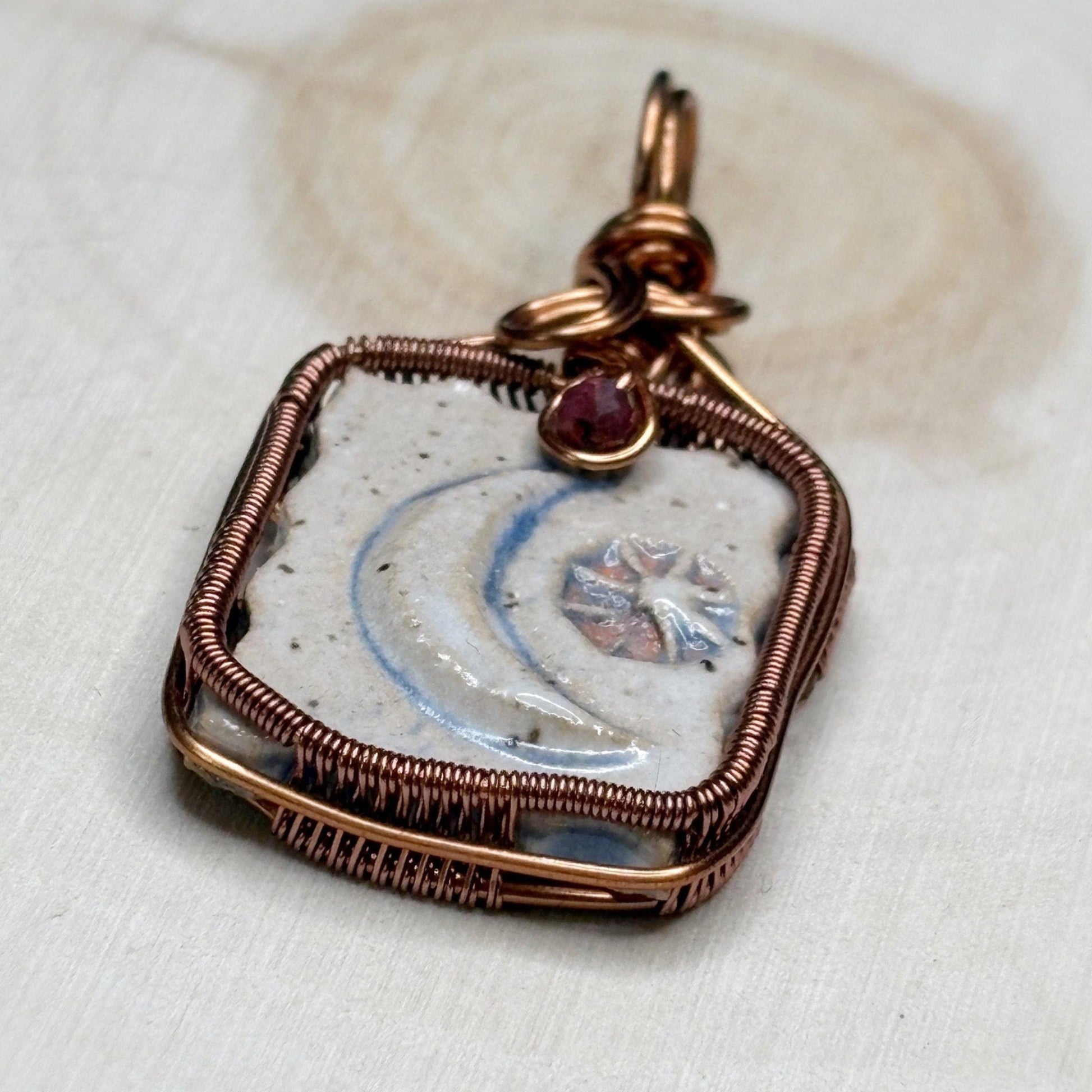 Decorative pendant with a gemstone on a white fabric background