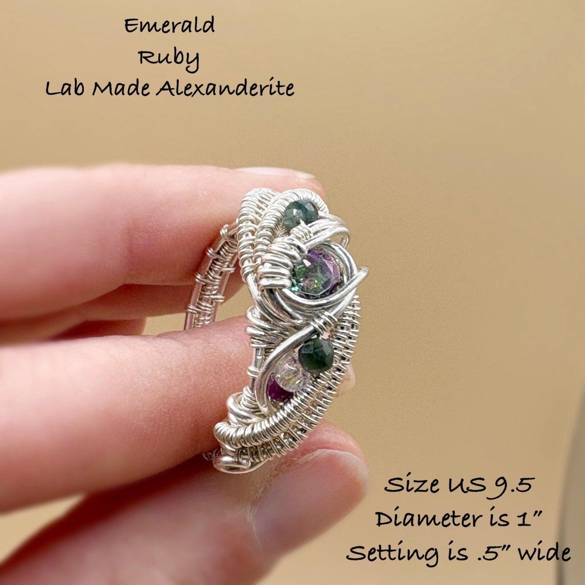 Silver wire-wrapped ring with gemstones held in a hand against a beige background