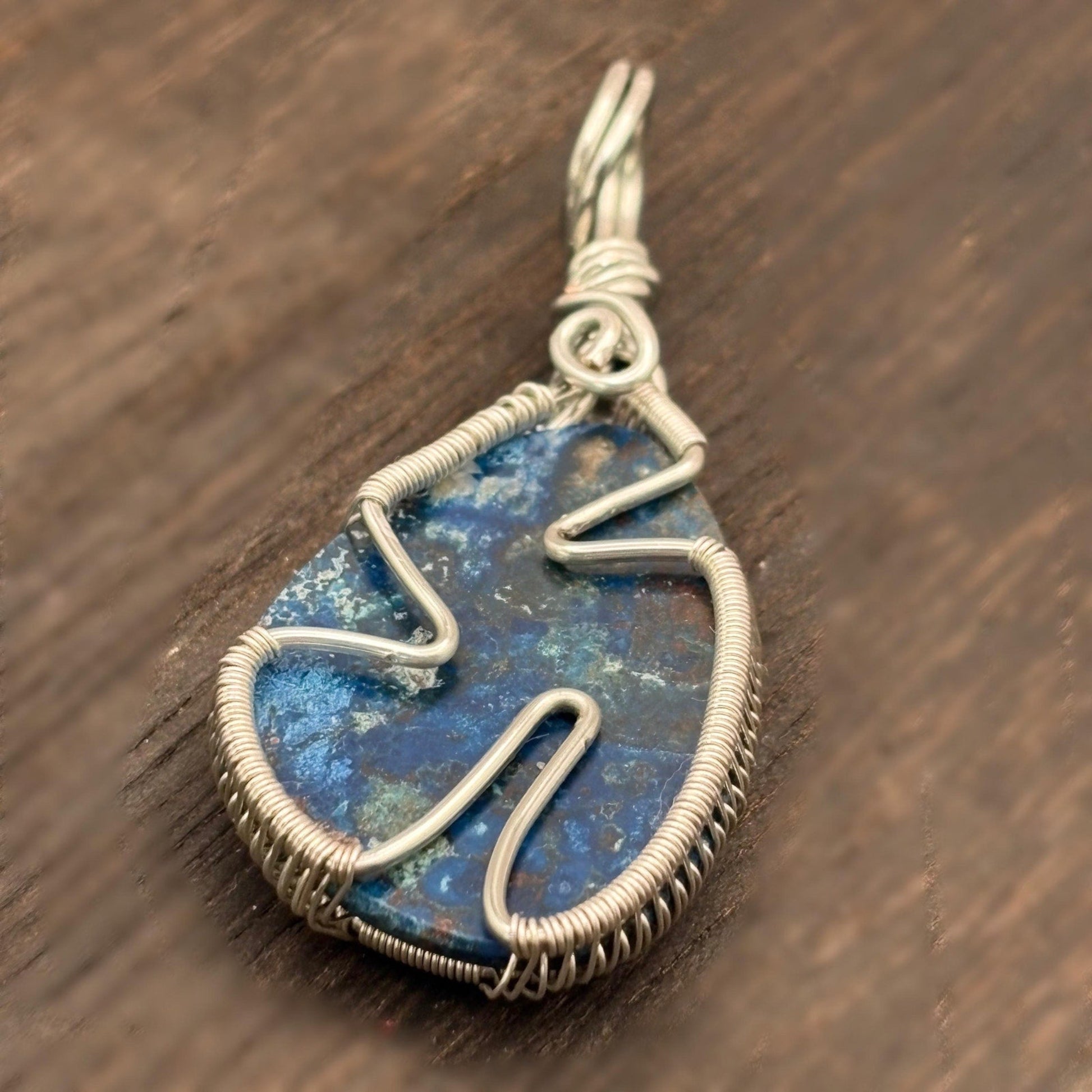 Silver-wrapped blue stone pendant on a wooden surface