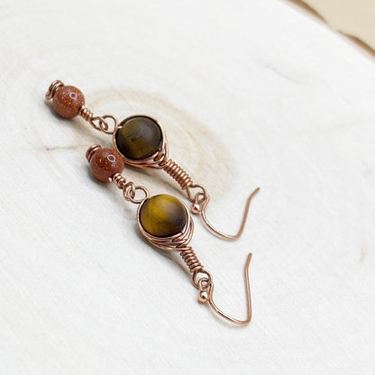 Pair of earrings with brown and gold beads on a white background