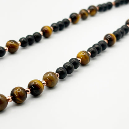Necklace with alternating black and brown beaded strands on a white background