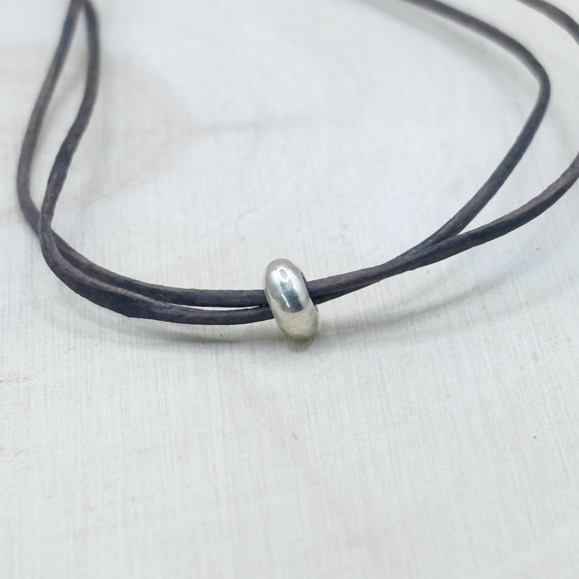 Black leather cord with a silver bead on a white background