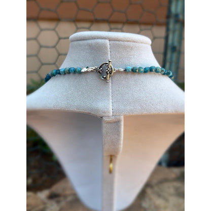 Blue apatite necklace on a white mannequin bust with a textured wall background