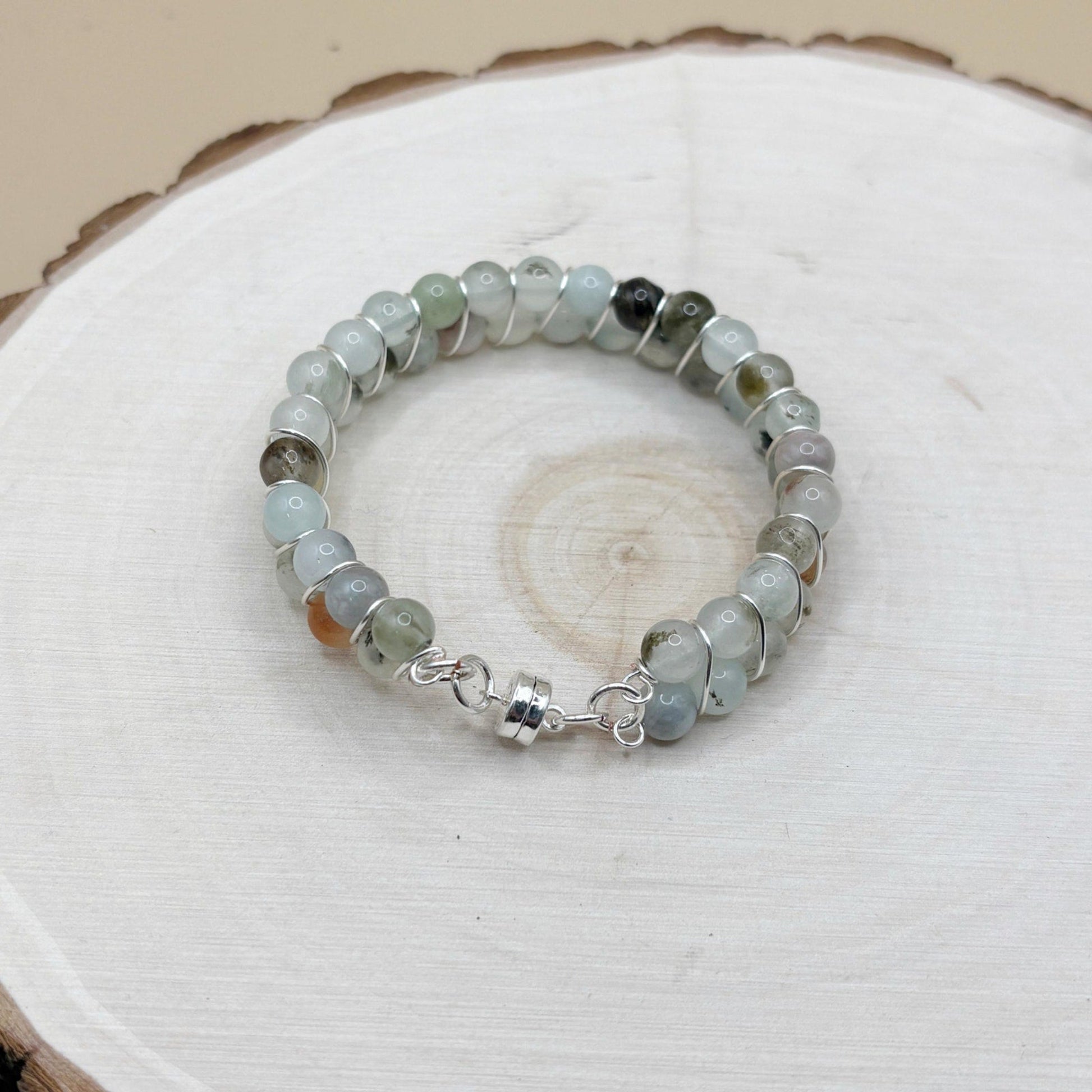 Beaded bracelet with silver clasp and transparent blue beads on a wooden surface