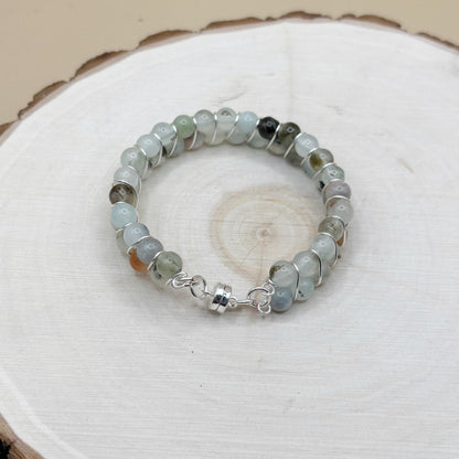 Beaded bracelet with silver clasp and transparent blue beads on a wooden surface