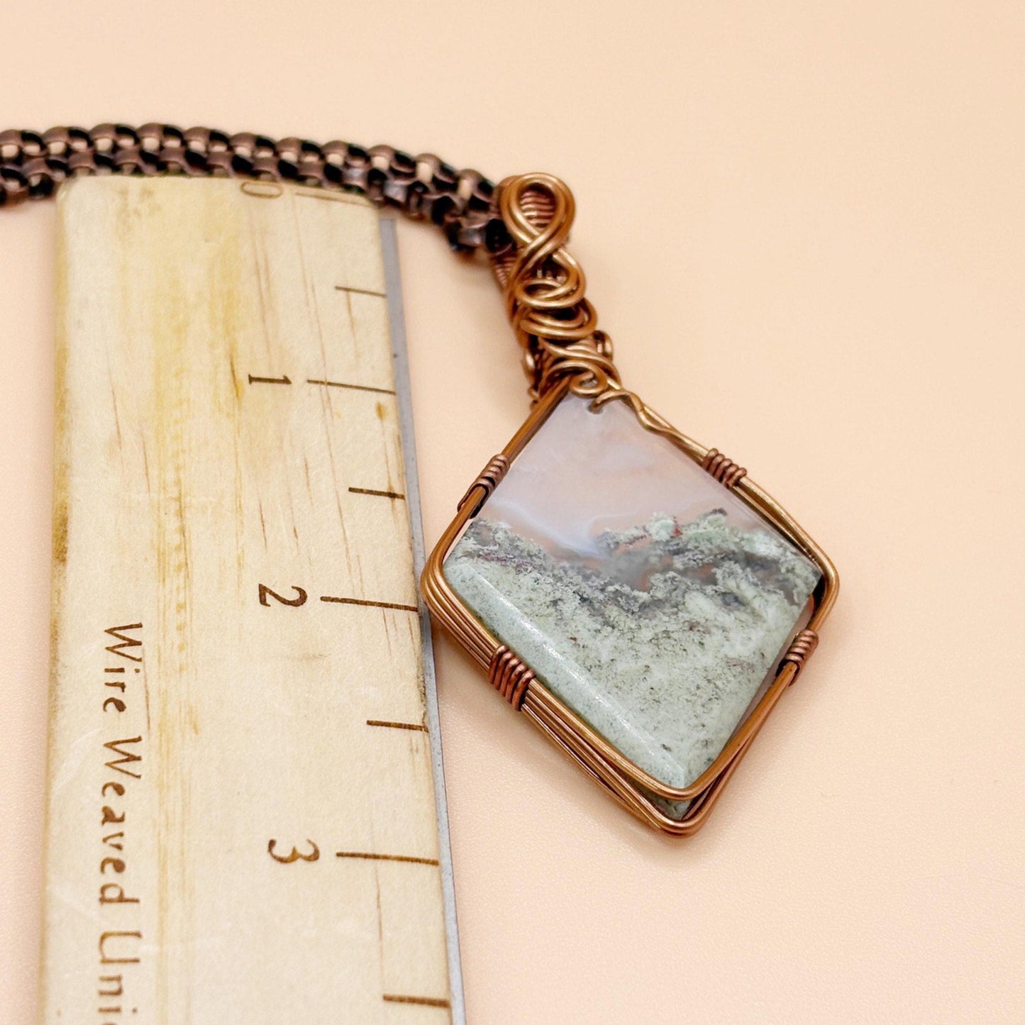 Necklace with a pendant on a wooden ruler for scale