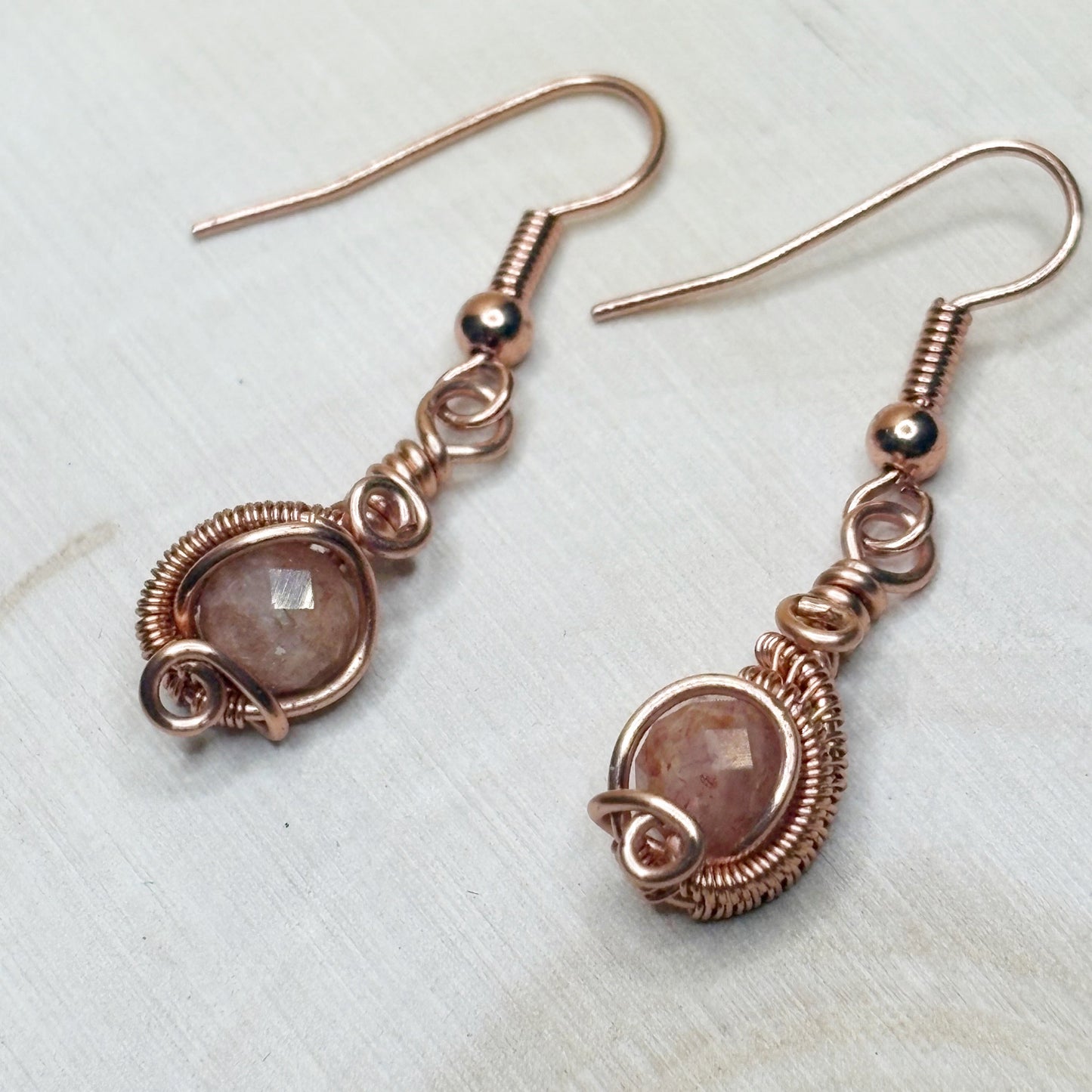 Copper wire-wrapped earrings with gemstones on a light background
