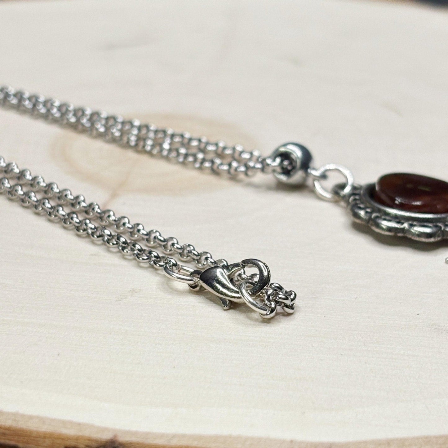Silver necklace with a pendant on a light wooden surface