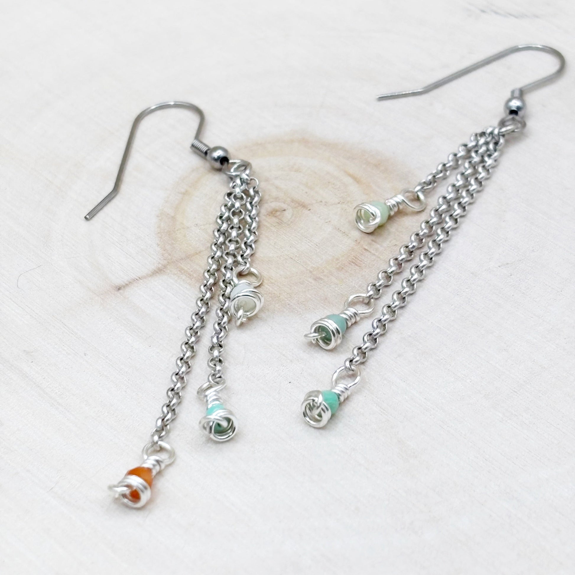 Silver chain earrings with colorful beads on a light background