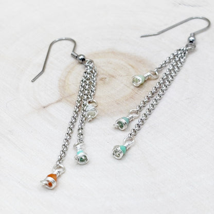 Silver chain earrings with colorful beads on a light background