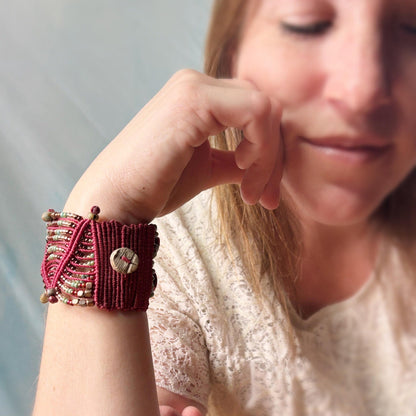 Close-up of a person wearing a red textured bracelet with a button-like charm.