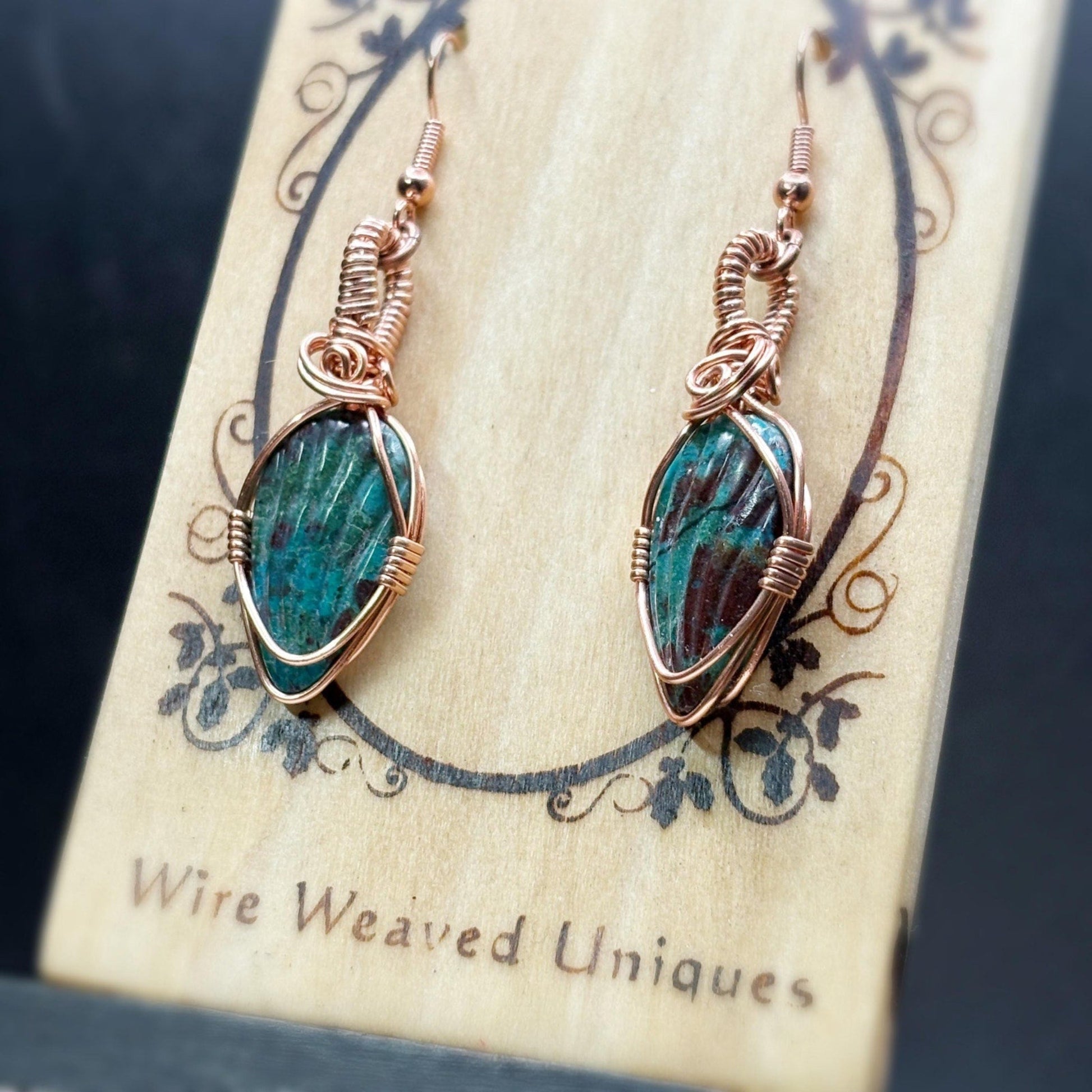 Pair of wire-wrapped earrings with green stones on a 'Wire Weaved Uniques' card.