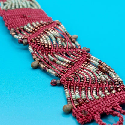 Beaded bracelet with red and green beads on a blue background