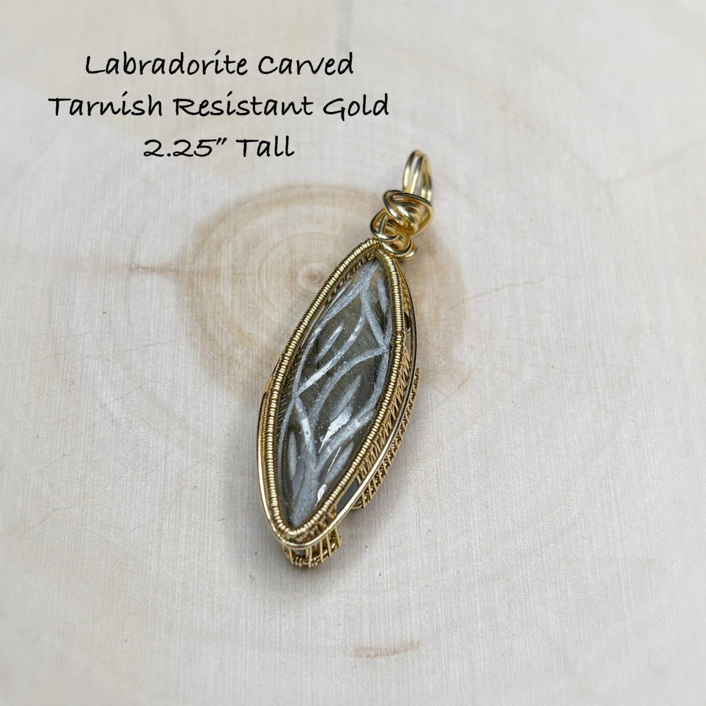 Gold pendant with labradorite stone on a textured beige background