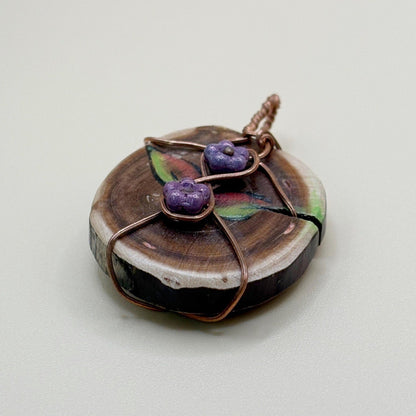 Handmade necklace with a wooden pendant and purple stones on a light background