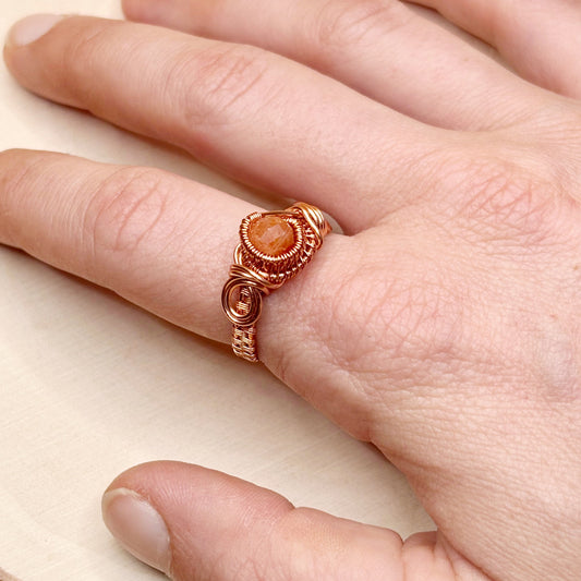 Copper ring with shiny stone in the center being modeled on hand