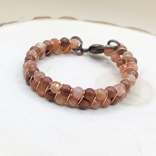 Beaded bracelet with brown and orange copper stones on a white wood surface-p