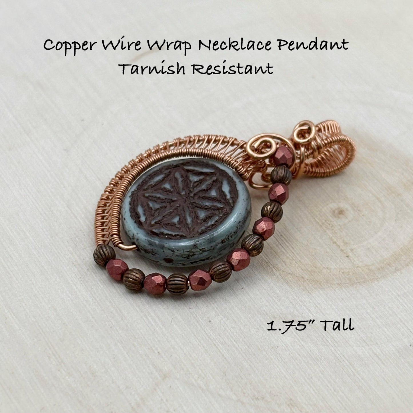 Copper wire wrap necklace pendant on a light wooden surface