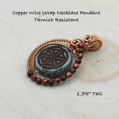 Copper wire wrap necklace pendant on a light wooden surface