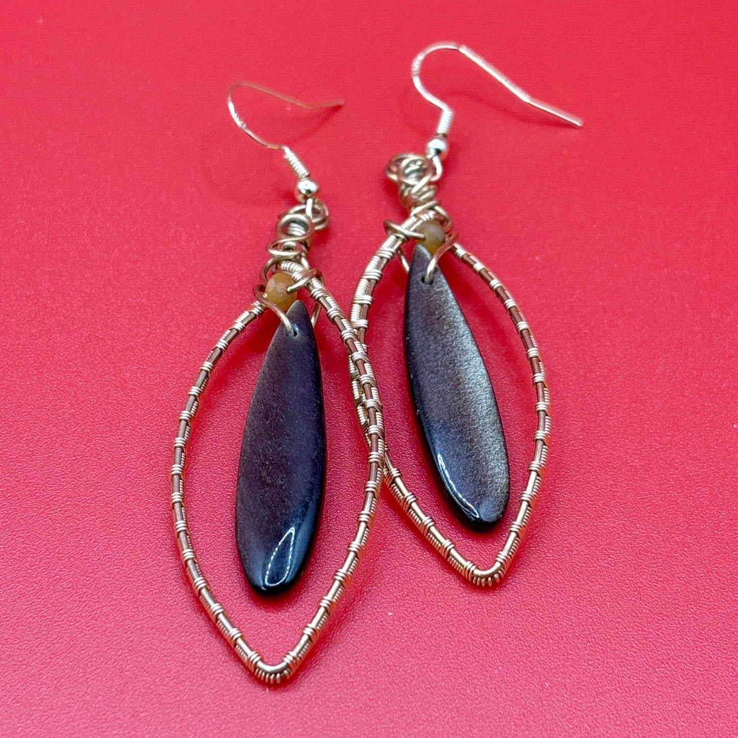 Pair of earrings with blue teardrop-shaped stones on a red background