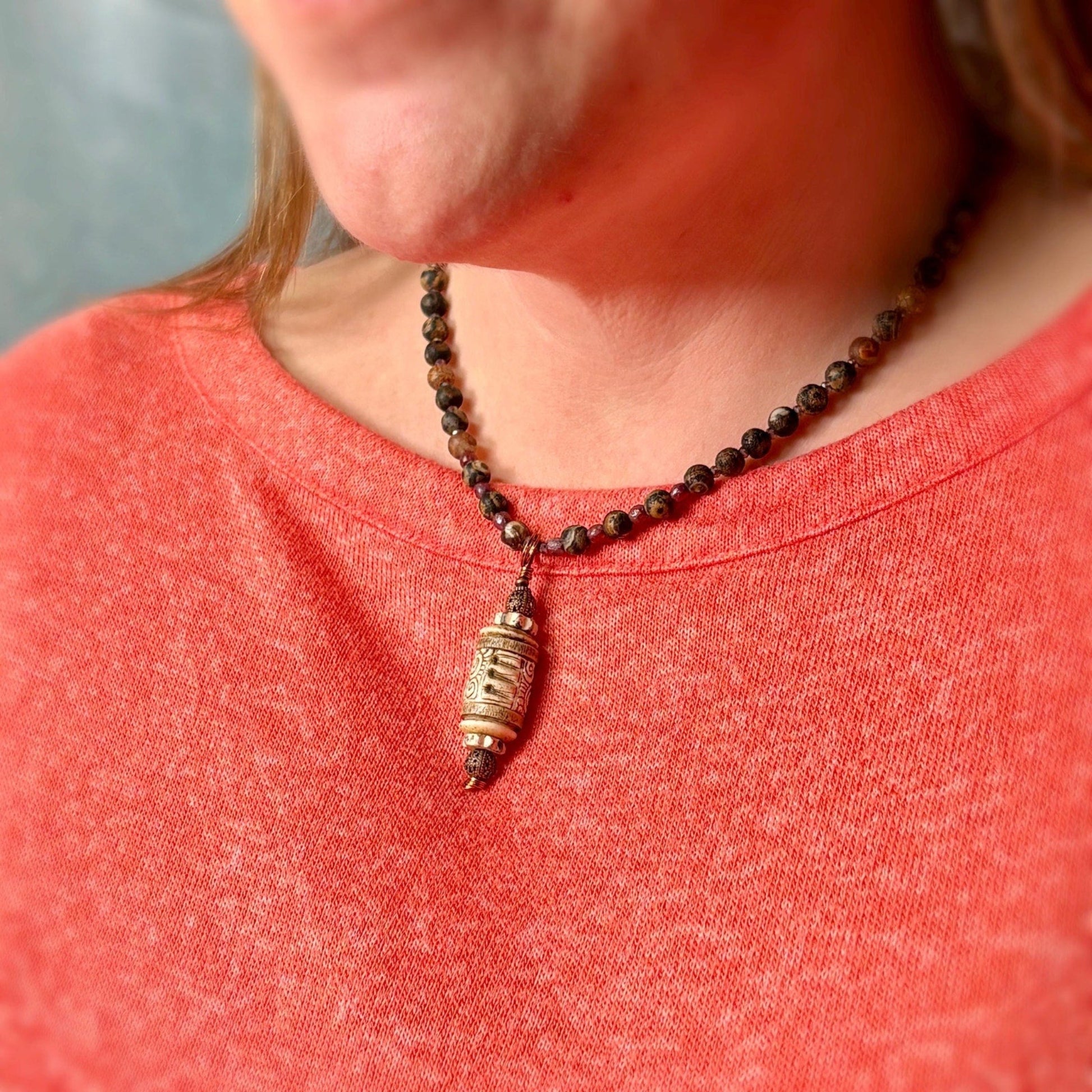 Necklace with a pendant worn by a person in a red shirt.