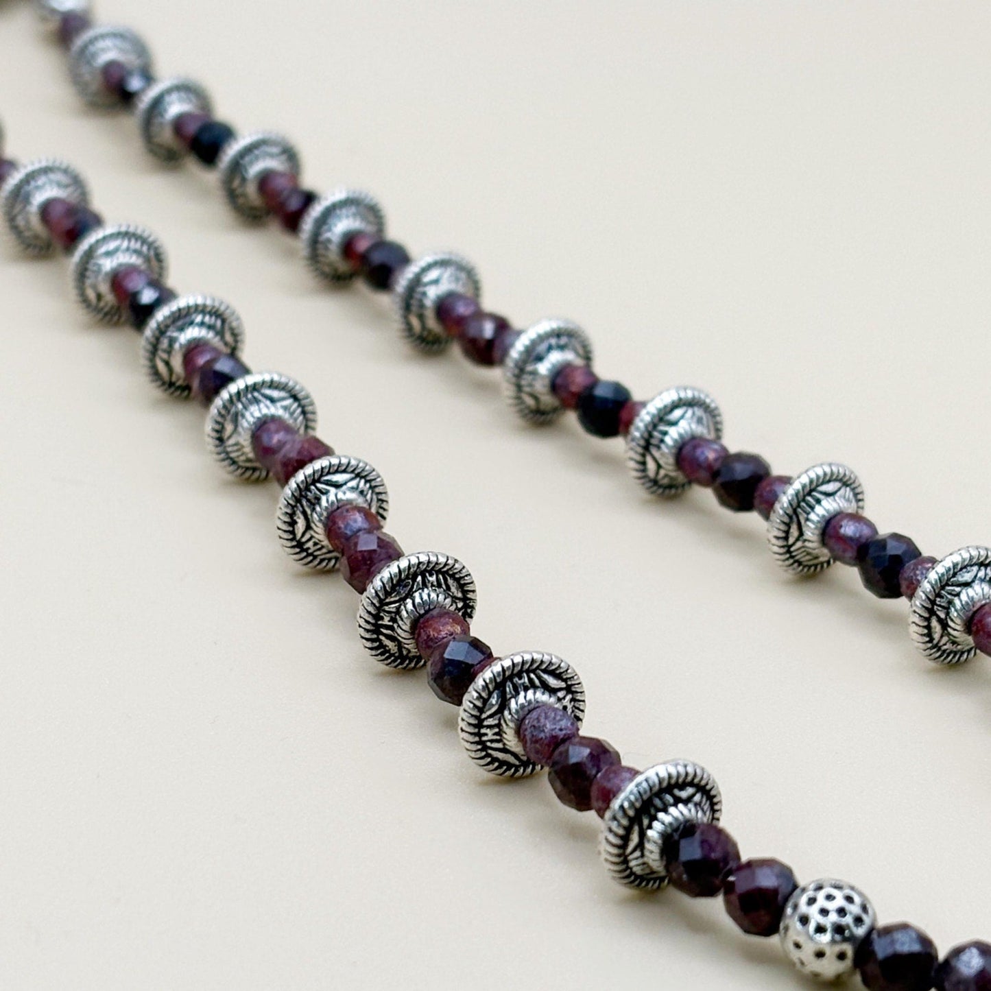 Necklace with silver and purple beads on a light background