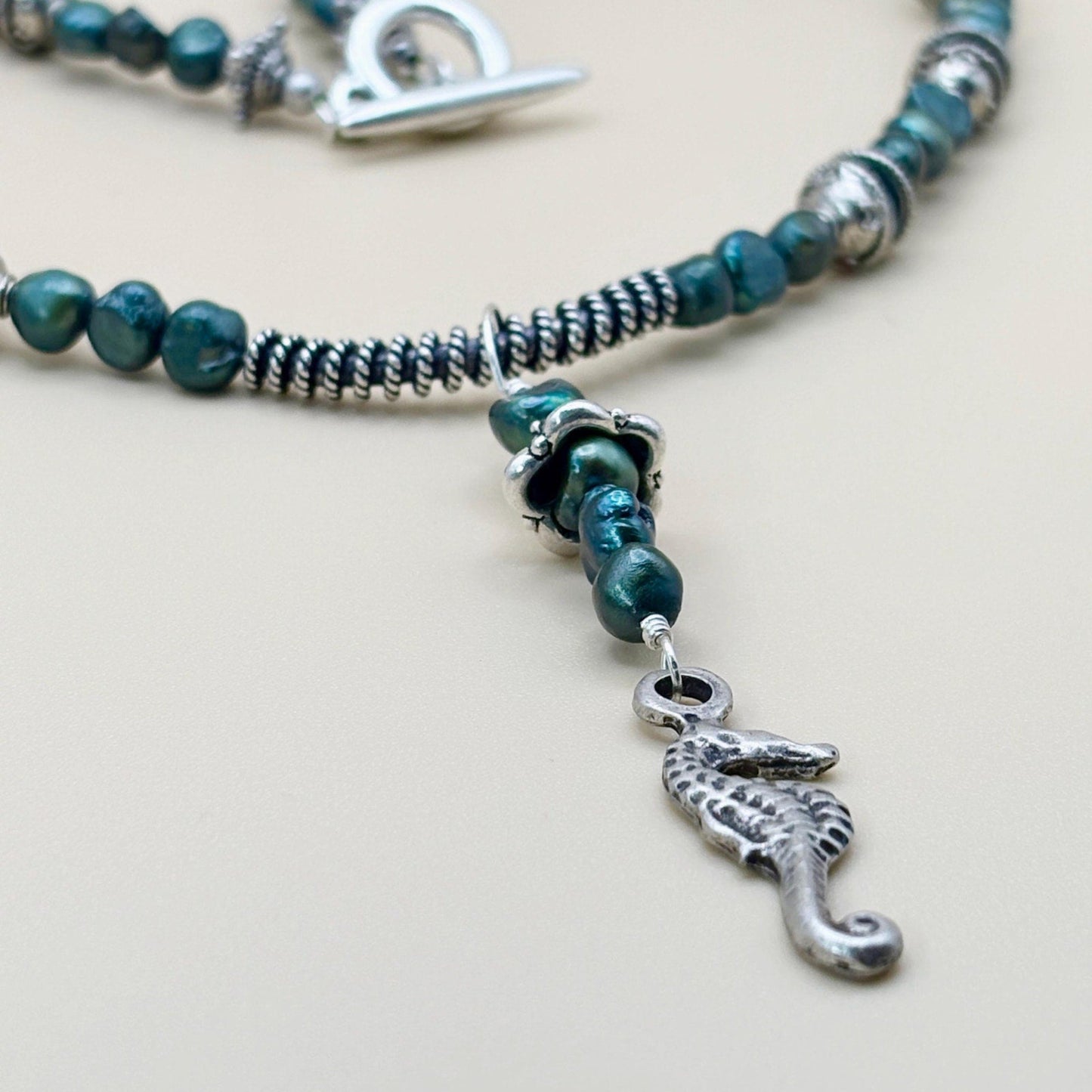 Beaded necklace with a silver seahorse charm on a light background