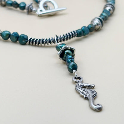Beaded necklace with a silver seahorse charm on a light background
