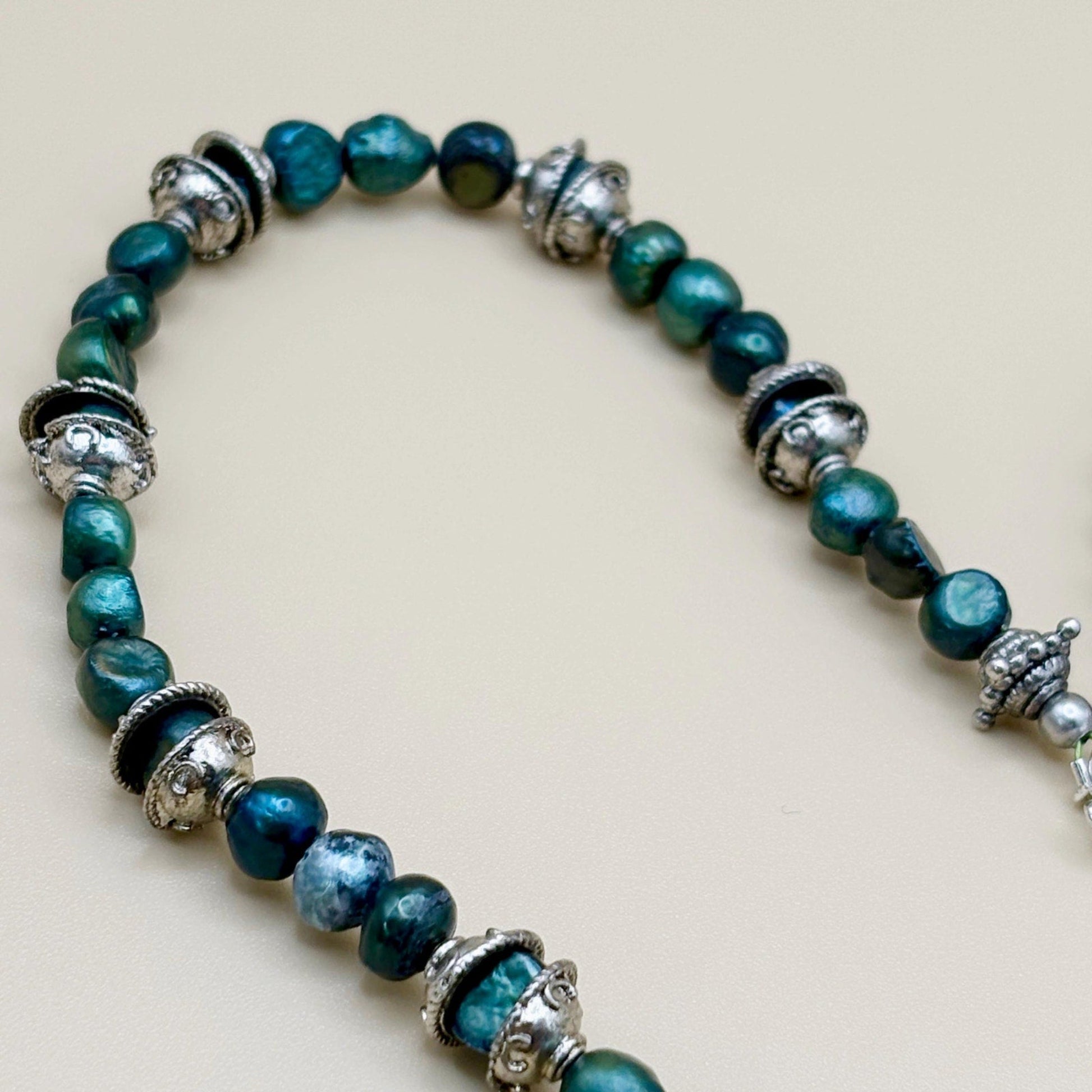 Bracelet with green pearl beads and silver accents on a light background