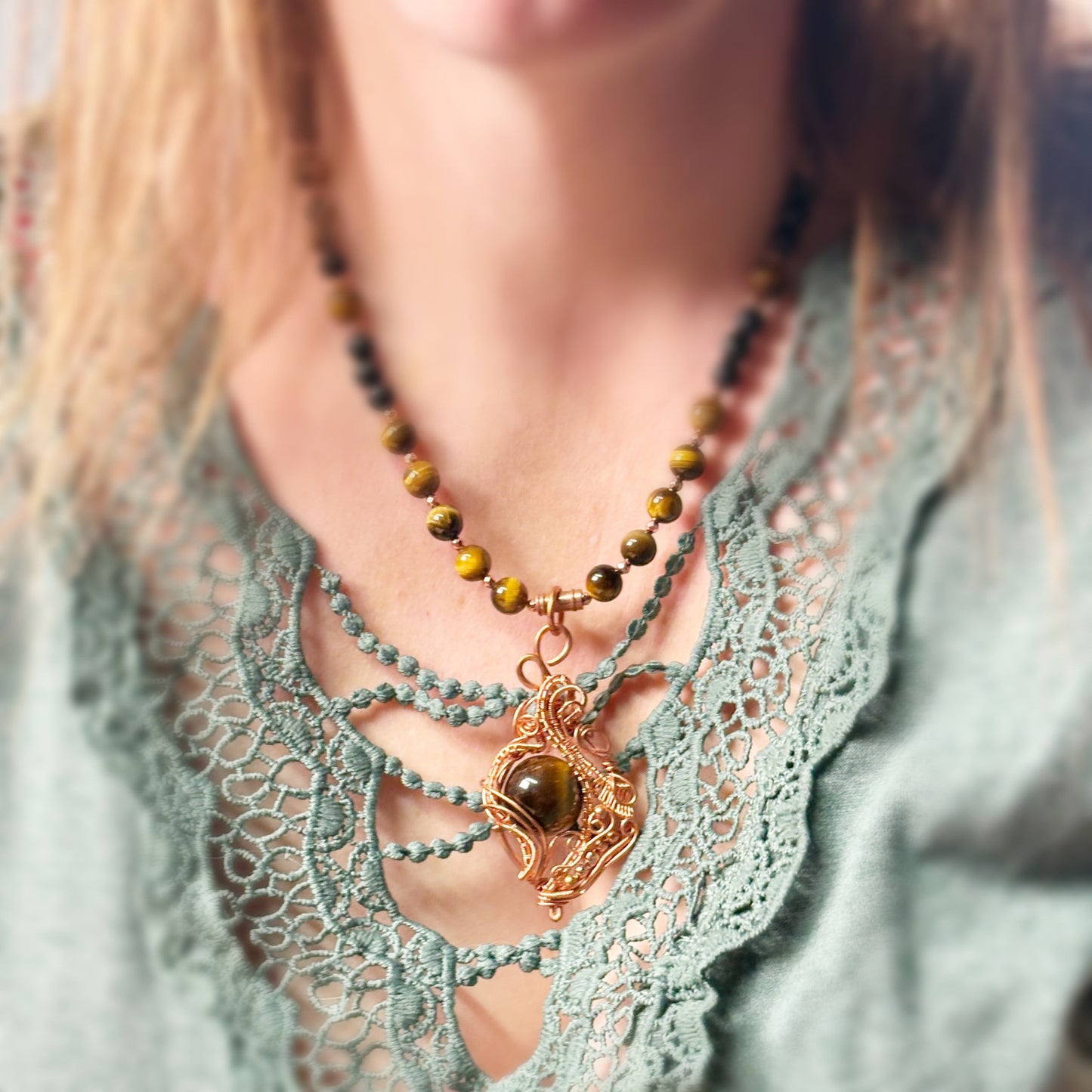 Necklace with green beads and a heart-shaped pendant on a person wearing a lace top.