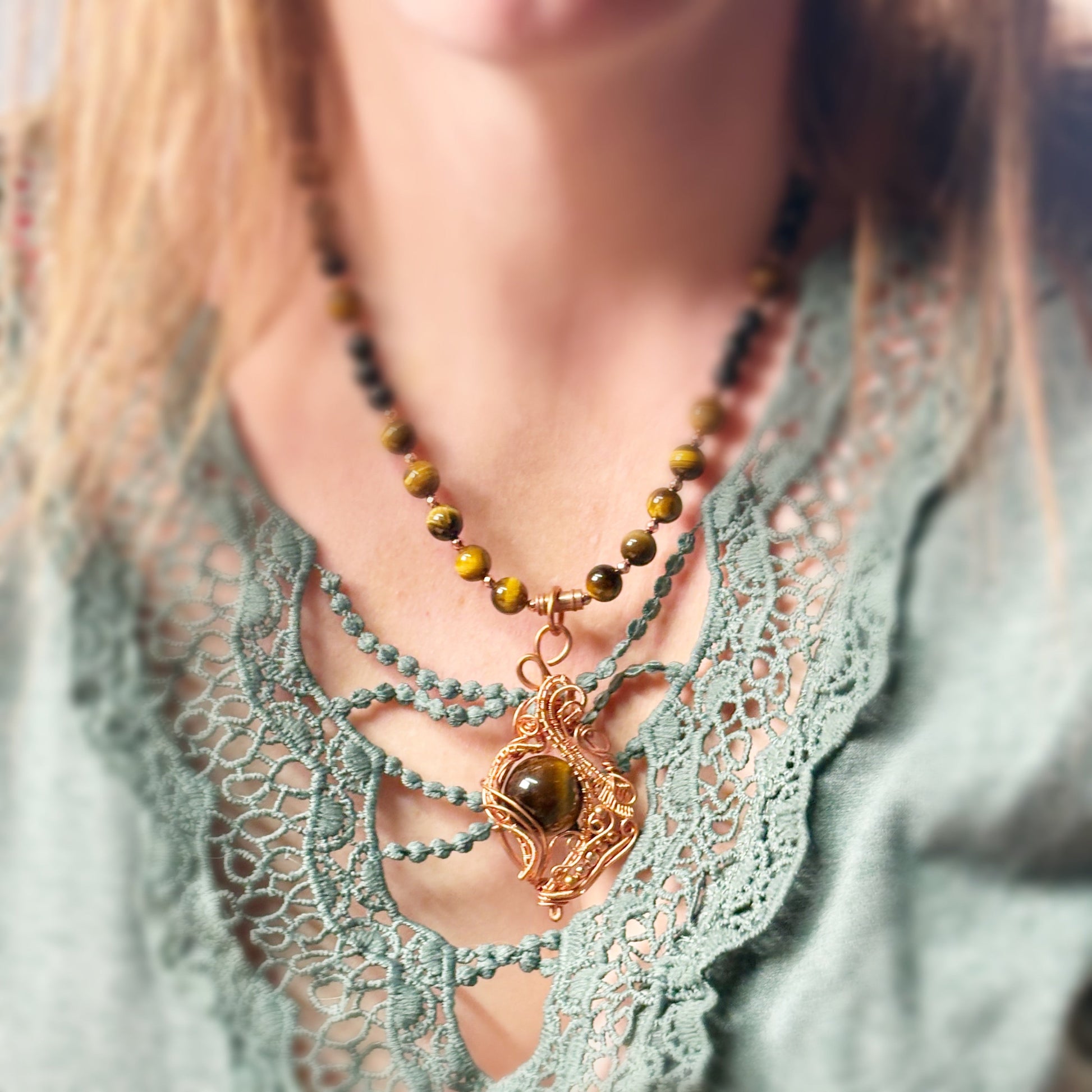 Necklace with green beads and a heart-shaped pendant on a person wearing a lace top.