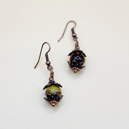 Pair of earrings with brown beads and copper accents on a light background