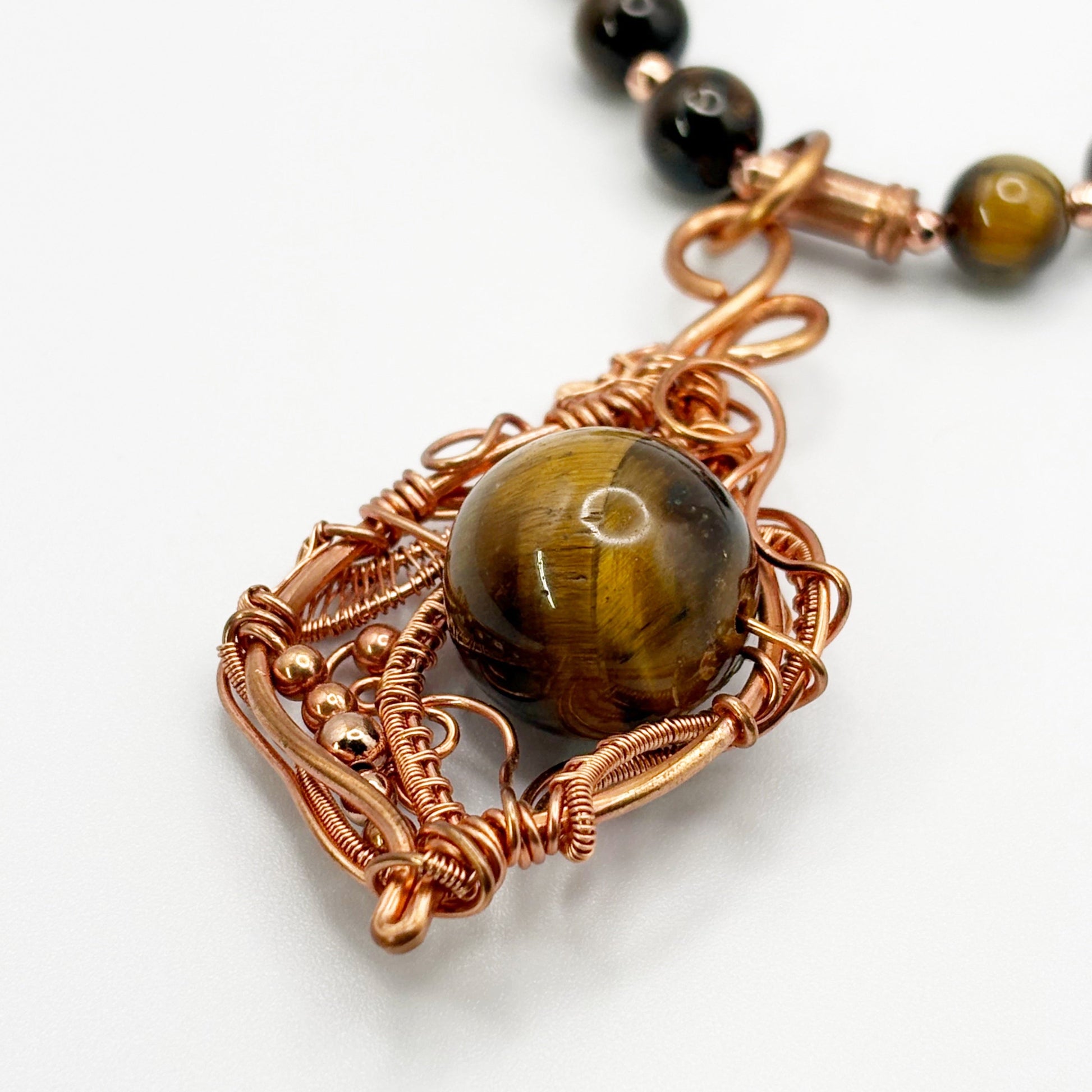Necklace with tiger's eye stone and copper wire wrapping on a white background